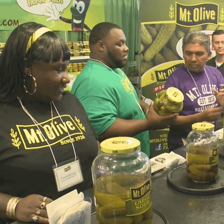 Mt. Olive Pickles booth at the N.C. State Fair with staff and jars of pickles.