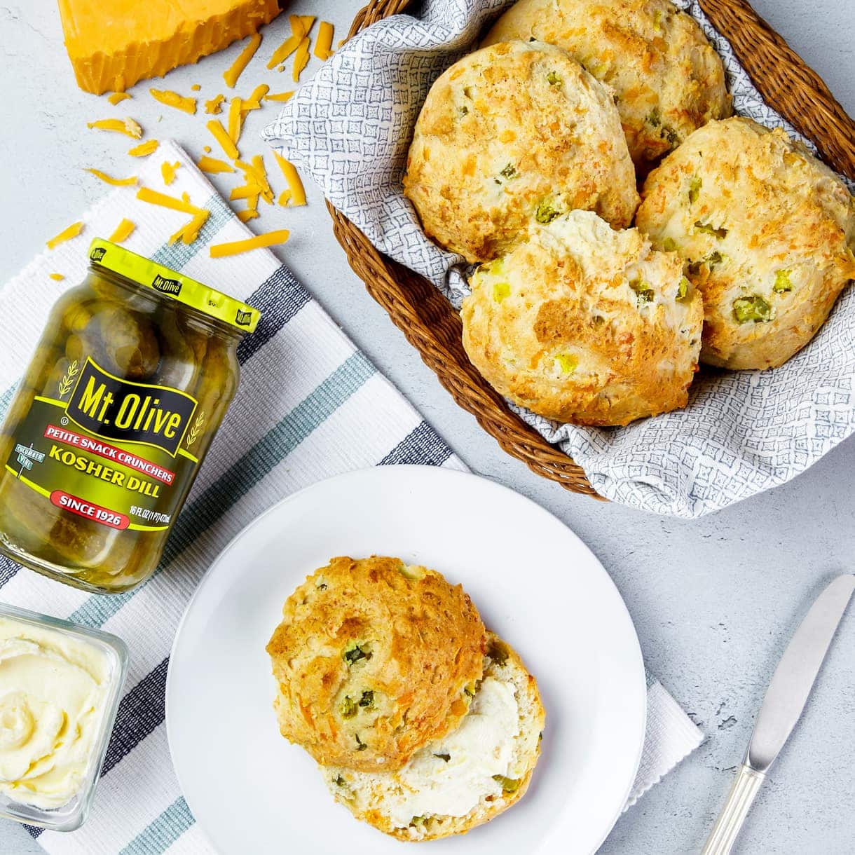 Biscuits with cheddar cheese and jar of kosher dill pickles. side of butter
