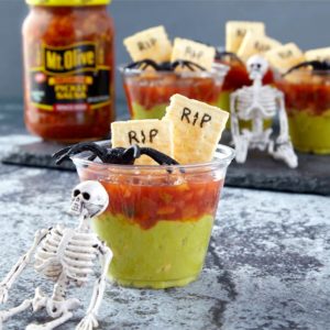 Pickle Salsa and Guacamole Cups with Crackers. Skeletons and Spiders on top of and next to cup