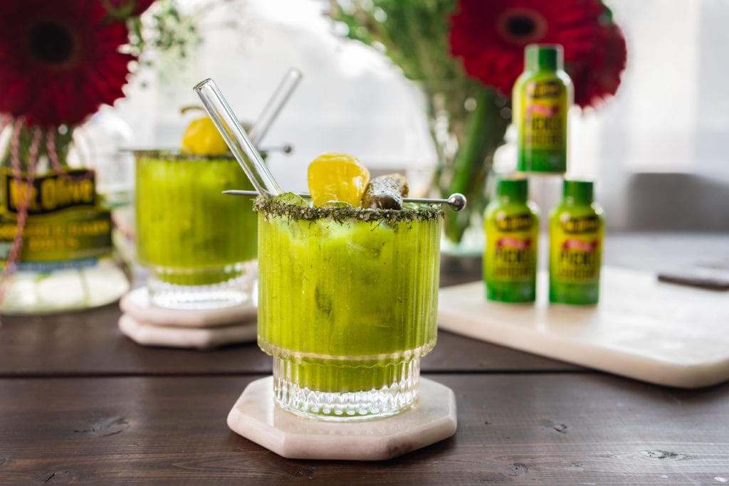 green pickle bloody mary with Pickle Juicers in the background