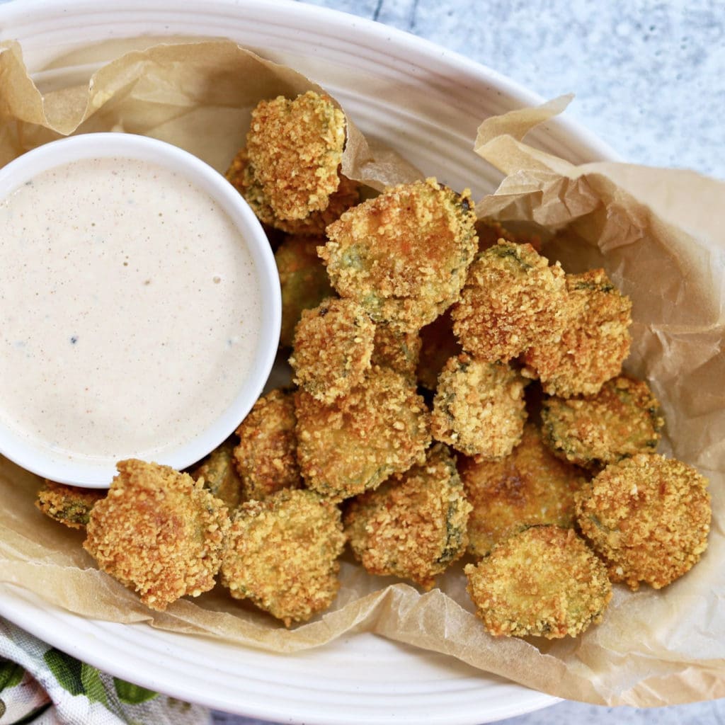 bowl of fried pickles with a side of ranch in white dish