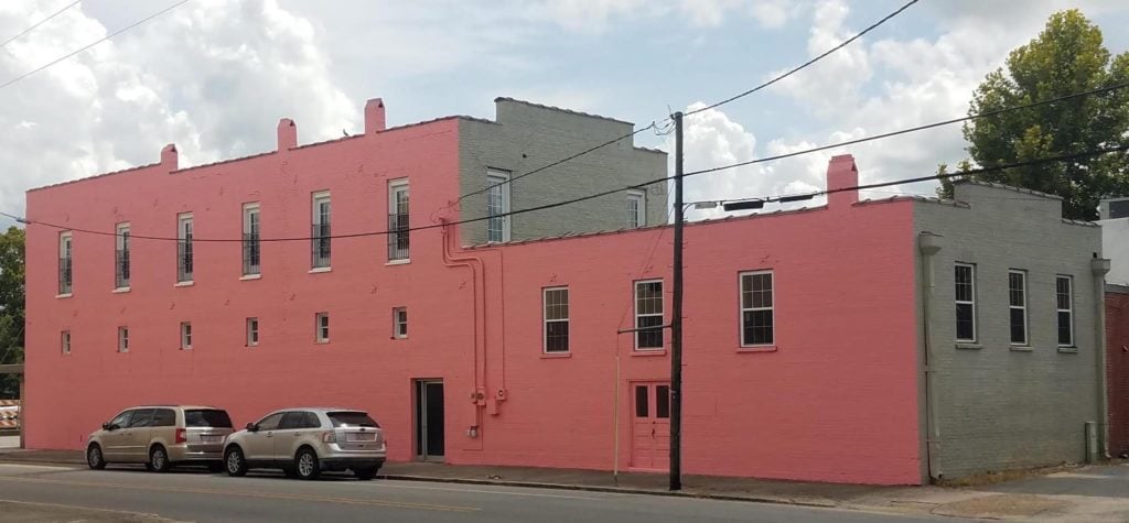 Vibrant pink and gray building on Main Street with parked cars in front.