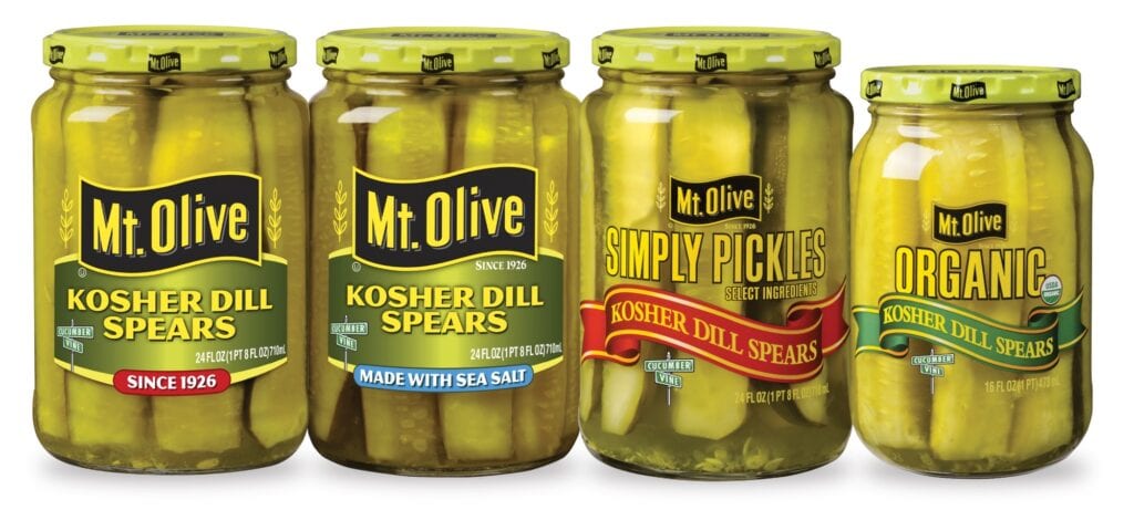 Four jars of pickles lined up. Kosher dill spears, simply pickles and organic
