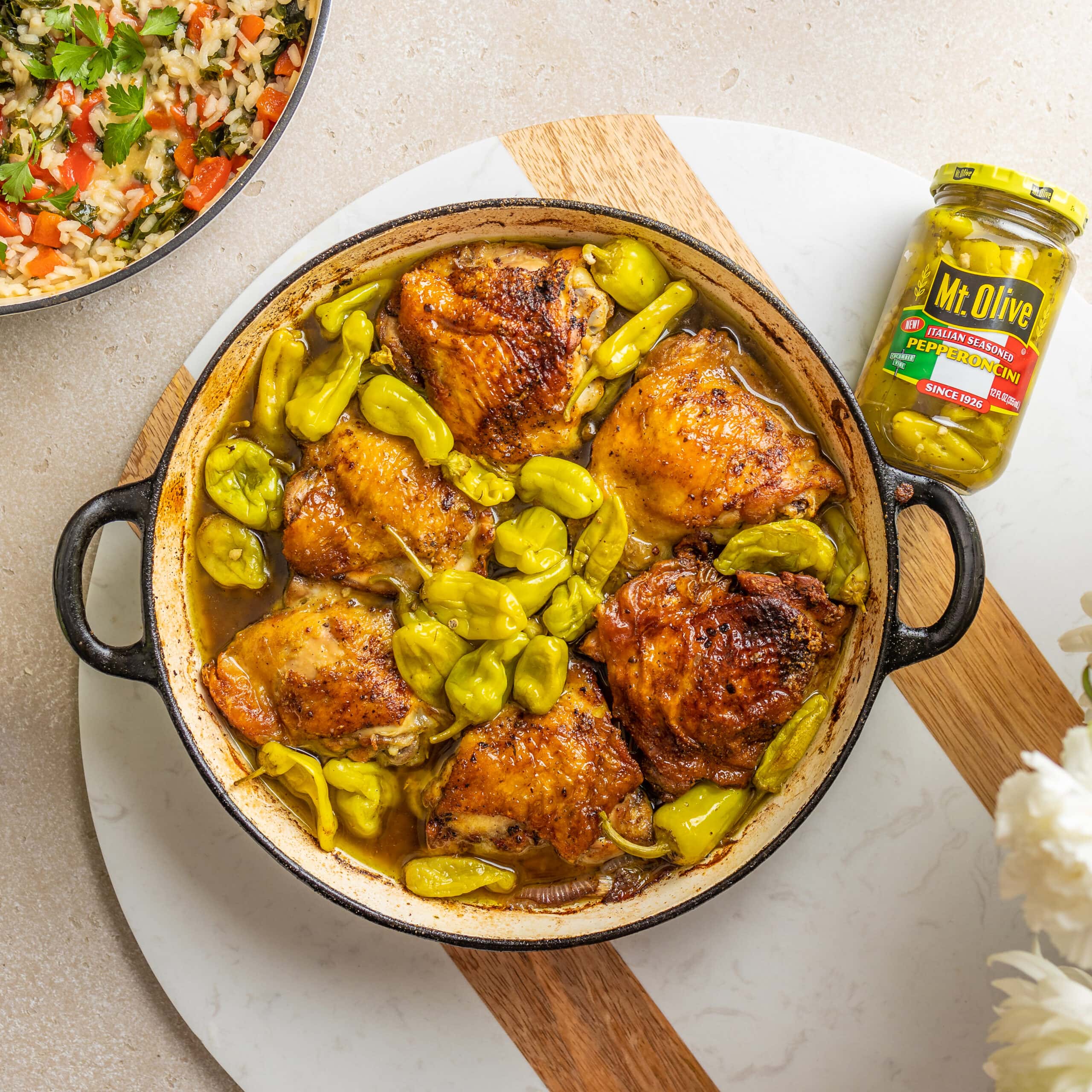 large pot of baked chicken surrounded by pepperoncini peppers and a jar of Italian Pepperoncinis