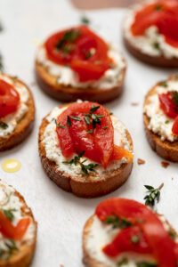 Close up of roasted red pepper crostini appetizer with cheese and garnish