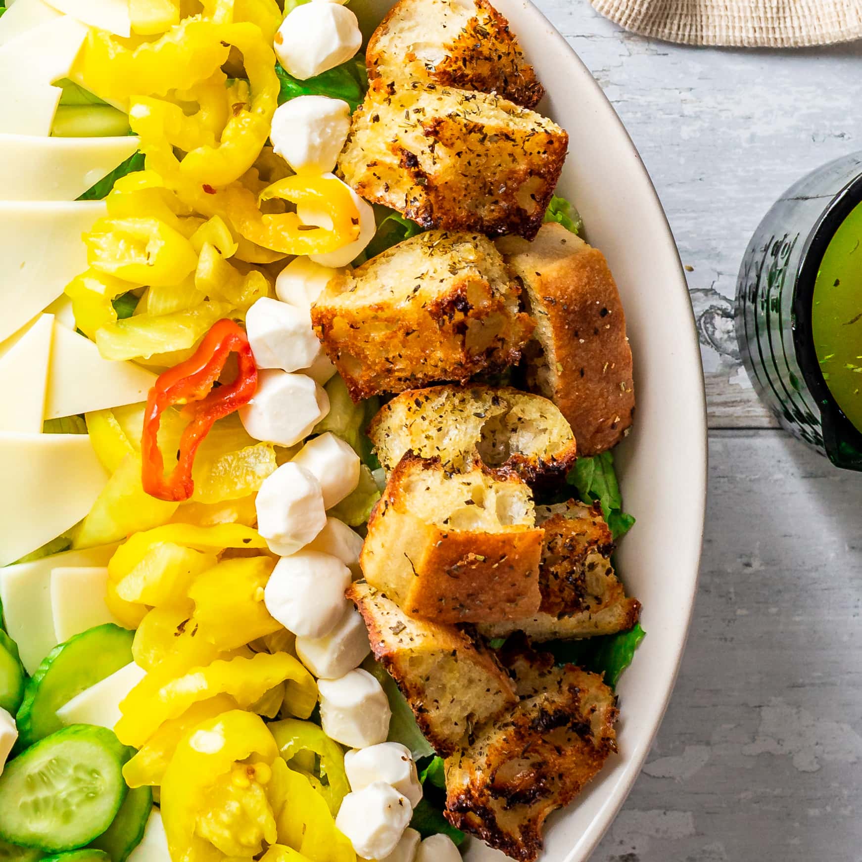 close up of salad chowing banana peppers, mozzarella cheese balls and homemade croutons