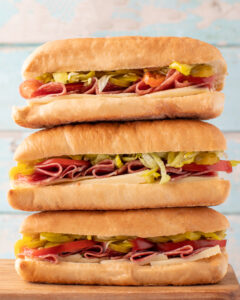 Stack of three italian sub sandwiches with meat and peppers