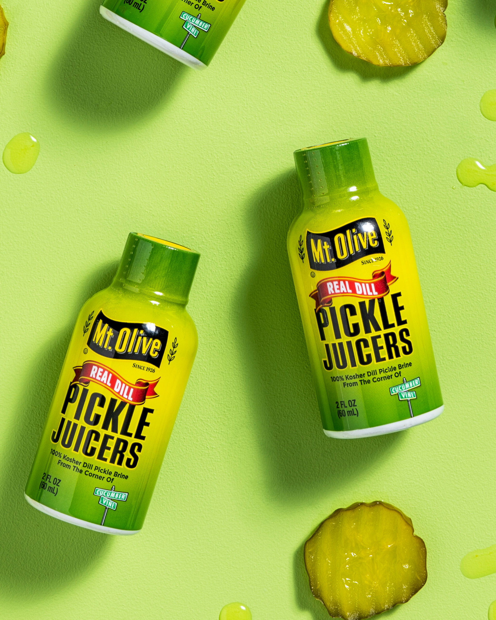 pickle juicers 2 oz bottles with pickle chips and droplets of pickle juice