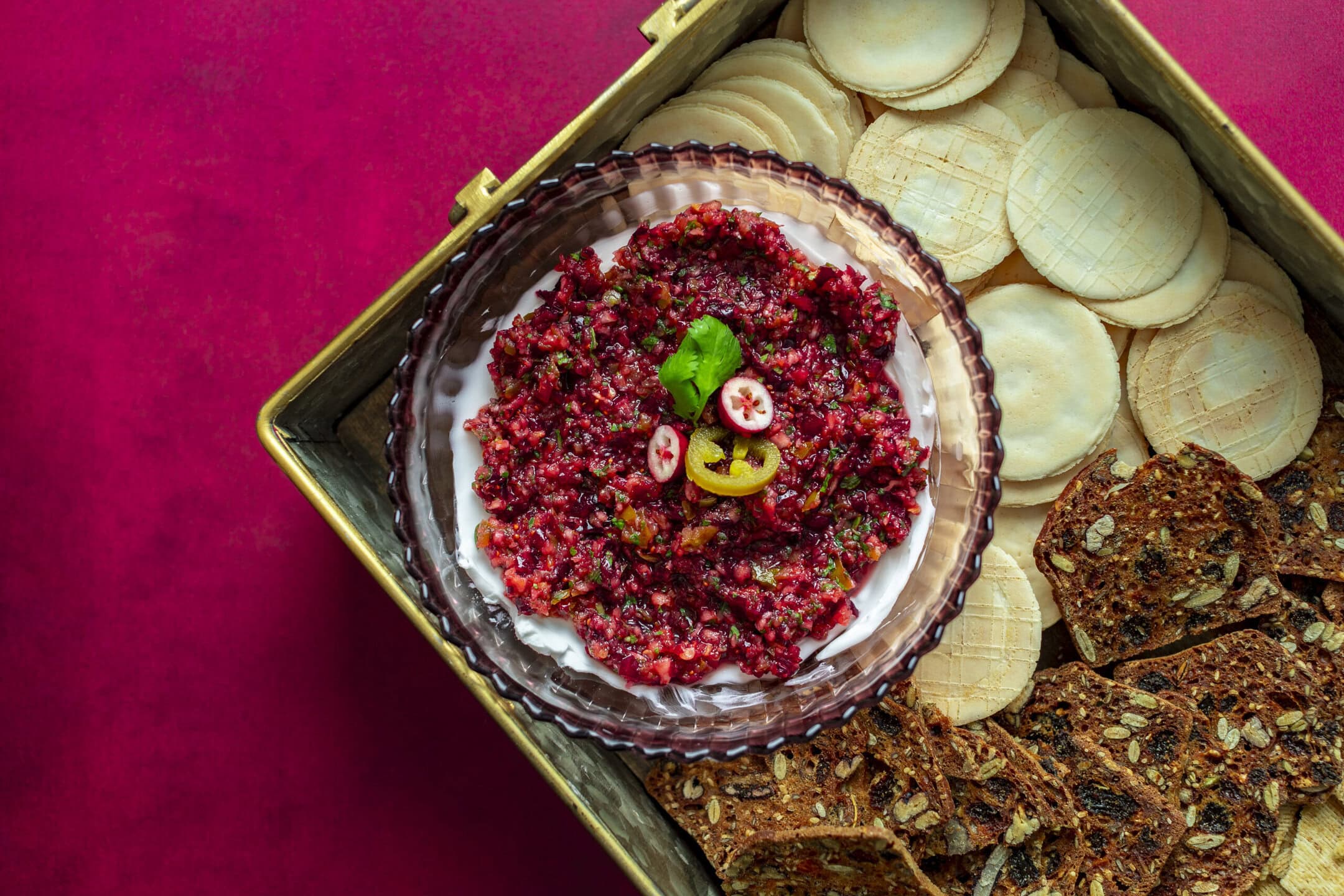 platter with crackers, and a dish with cream cheese and cranberry jalapeno relish topped with a jalapeno.