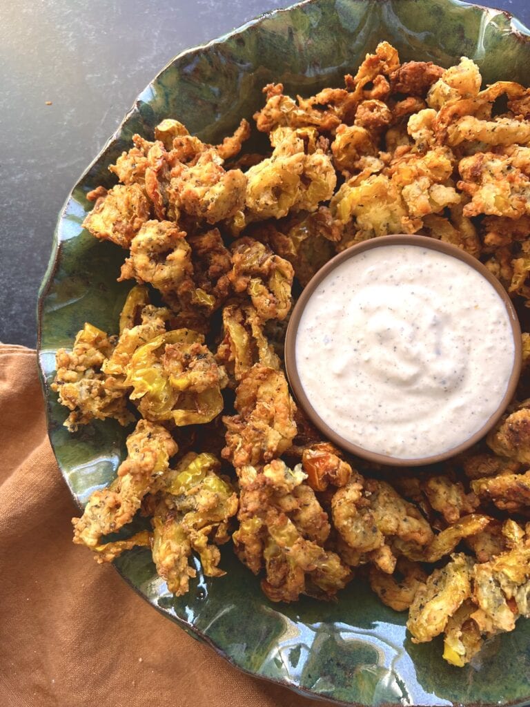 platter of fried banana peppers with peppercorn dipping sauce in the middle
