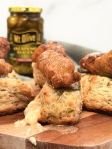 close up of a jalapeno biscuit mini bite topped with chicken nugget and jar of jalapenos in the background