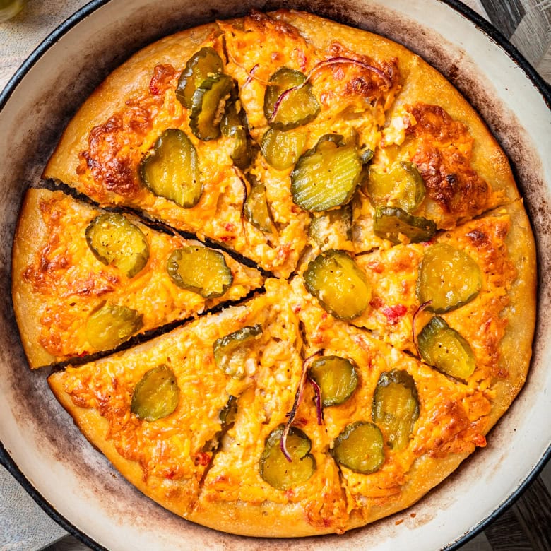 Pimento cheese pizza with pickle slices in a cast iron skillet