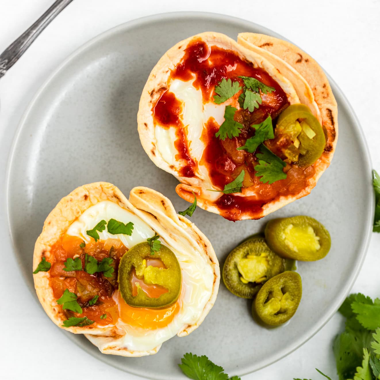 Huevos Rancheros Cups on a grey plate with jalapenos on the side and on top