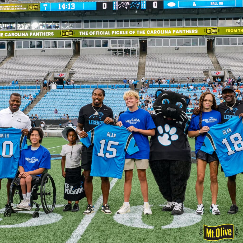Carolina Panthers players and Make-A-Wish alumni on the field with Mt. Olive Pickles mascot.