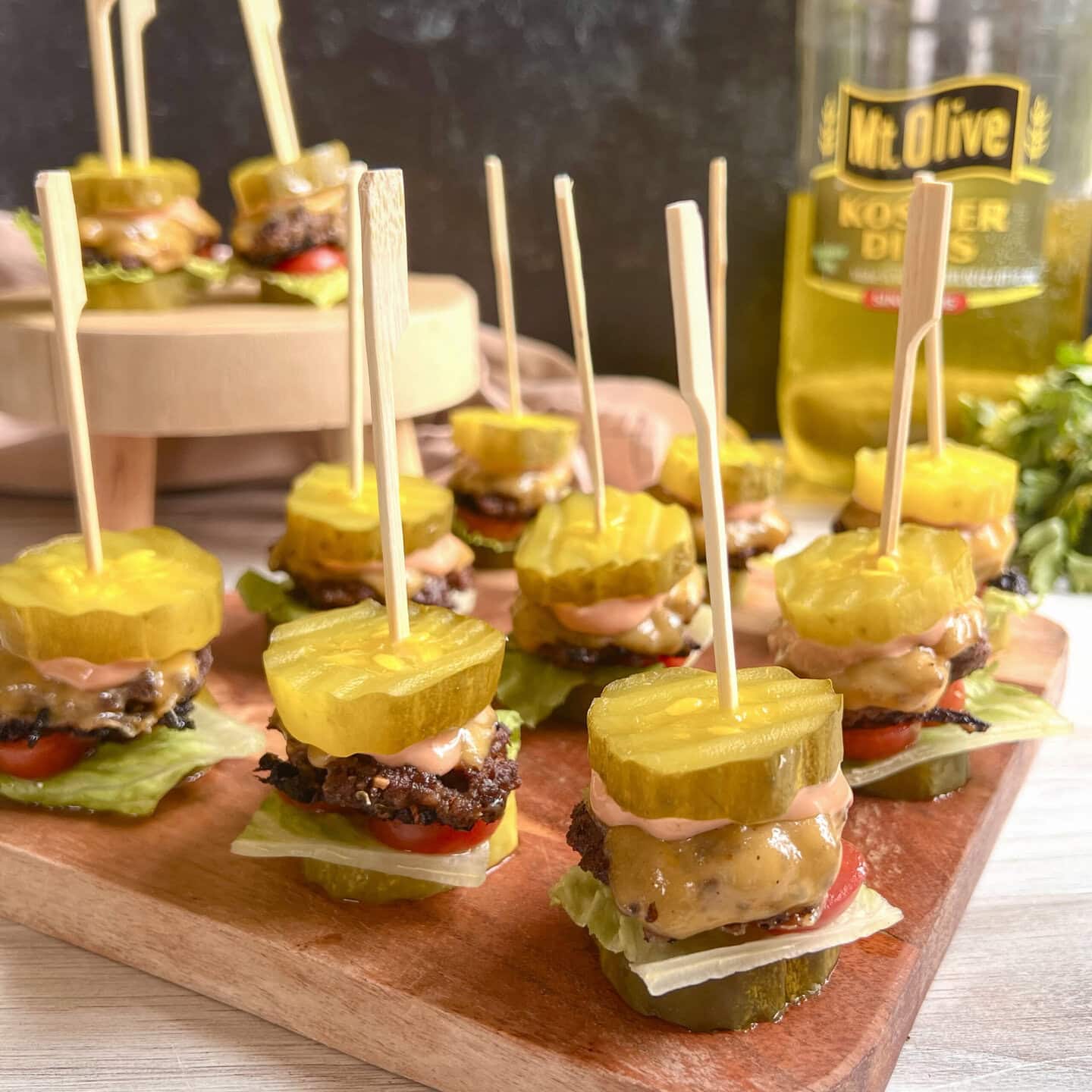 Mini burger sliders with pickle chip as buns on cutting board