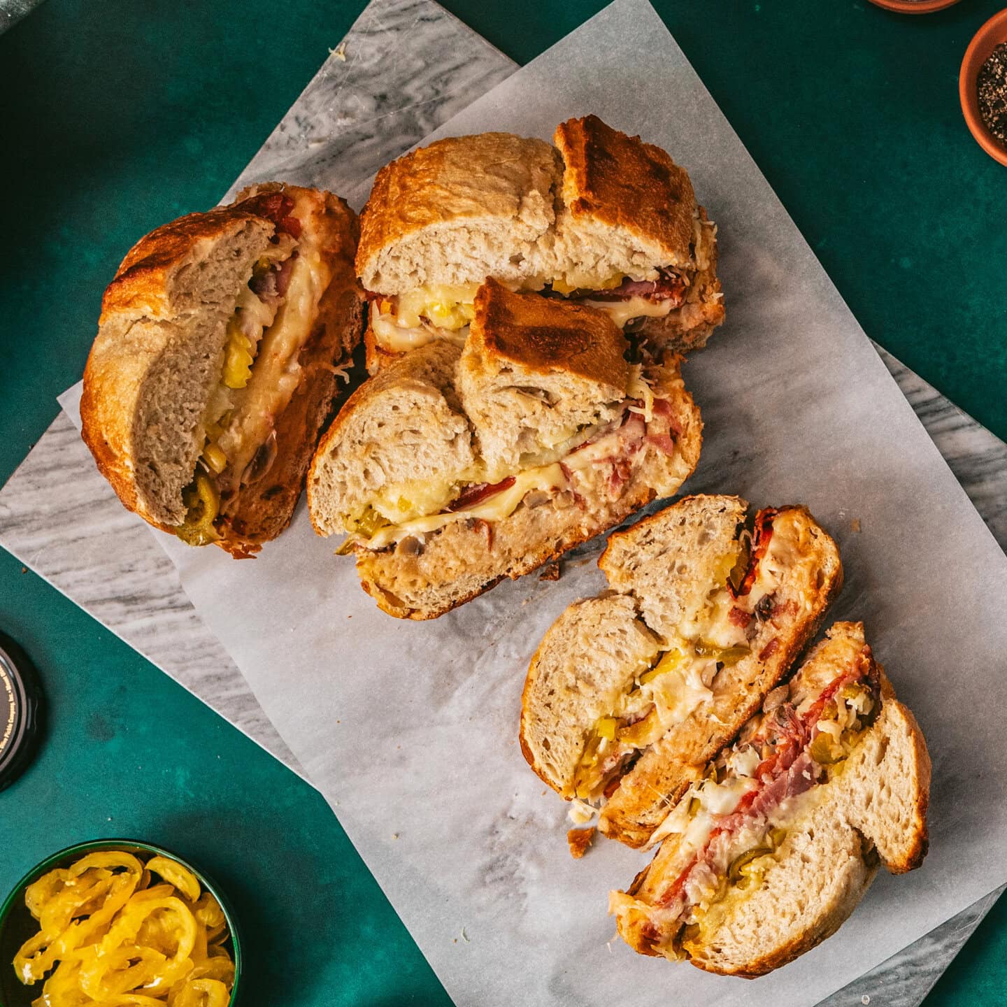 A large loaf of bread made into apn Italian Party Melt sandwich in 5 servings sitting on parchment paper.