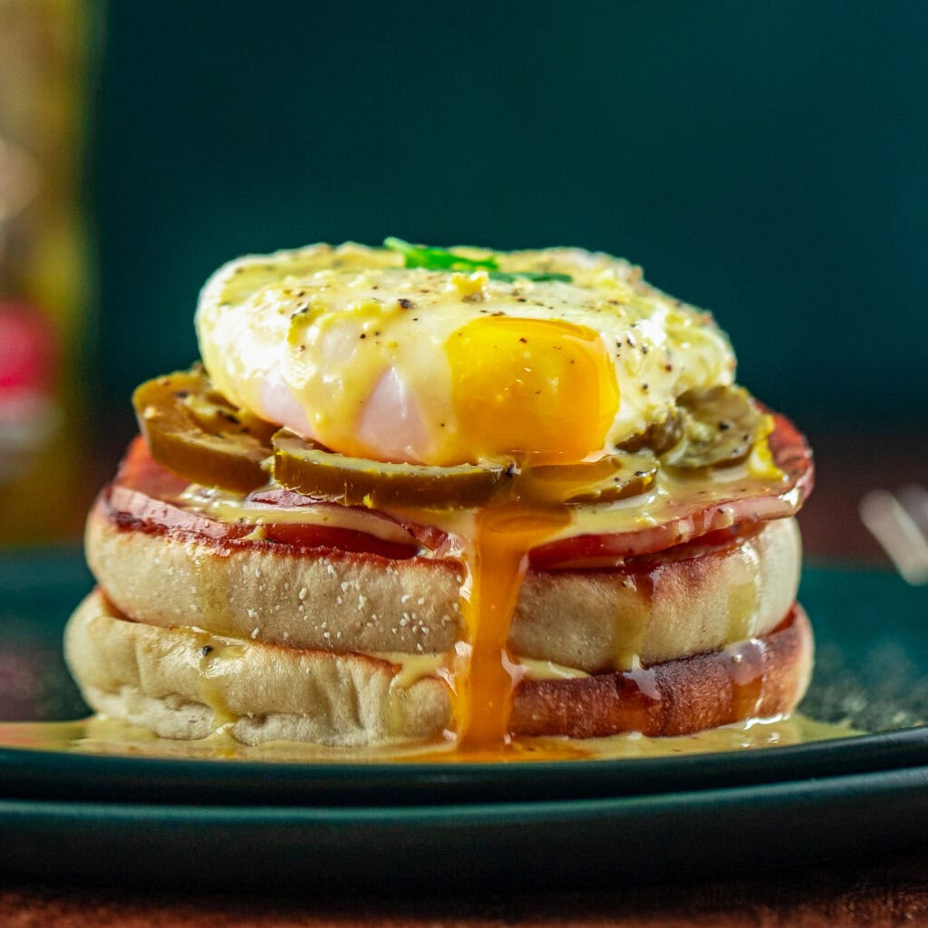 Jalapeno Hollandaise Eggs Benedict on a plate with egg yolk running down the English muffin.