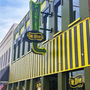 Mt Olive Pickles storefront with colorful signage and striped awning.