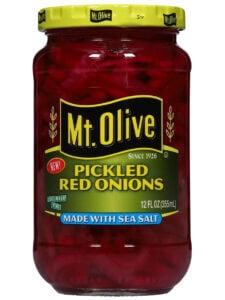The front of a jar of Mt. Olive Pickled red onions sits against a white backdrop.