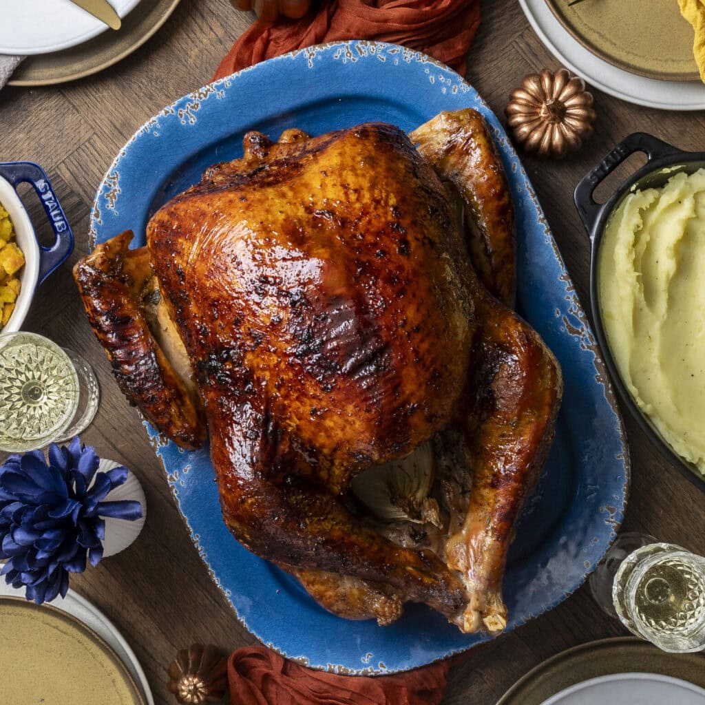 A whole roasted turkey on a blue plate with sides.