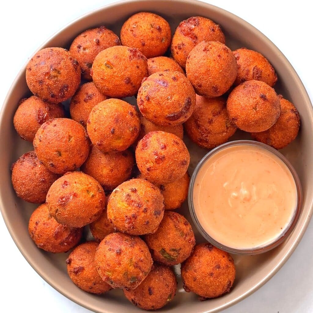Crispy Cornbread Bites or fried balls of cornbread in a bowl with dipping sauce.