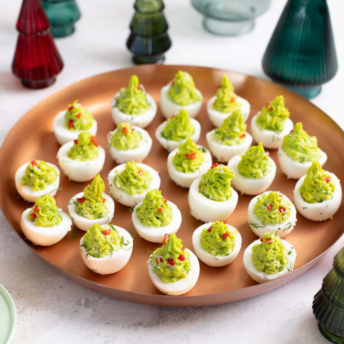 Platter of Christmas-tree inspired deviled eggs with glass Christmas trees for decoration.