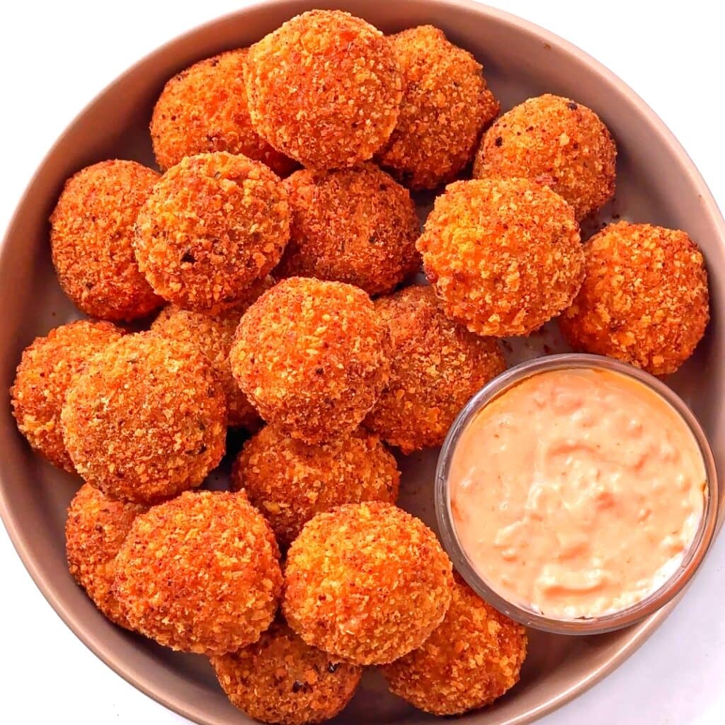 Crunchy cranberry jalapeno dip balls with dipping sauce in a bowl.