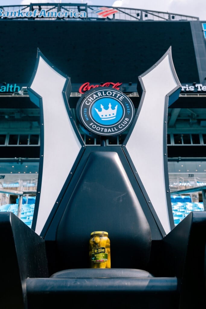 Charlotte FC logo at Bank of America Stadium with Mt Olive Pickles jar in foreground.