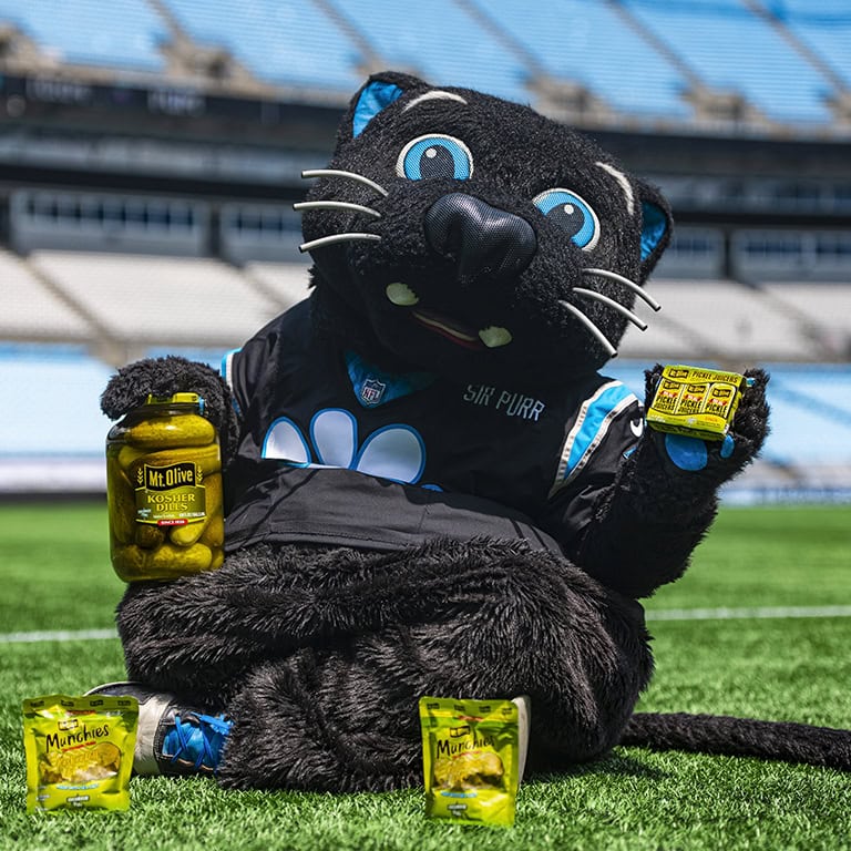 Mt Olive Pickles mascot at the Carolina Panthers stadium holding a jar of pickles.