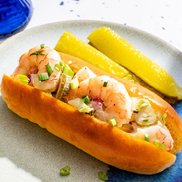 Shrimp roll with pickles and green onions on a plate.