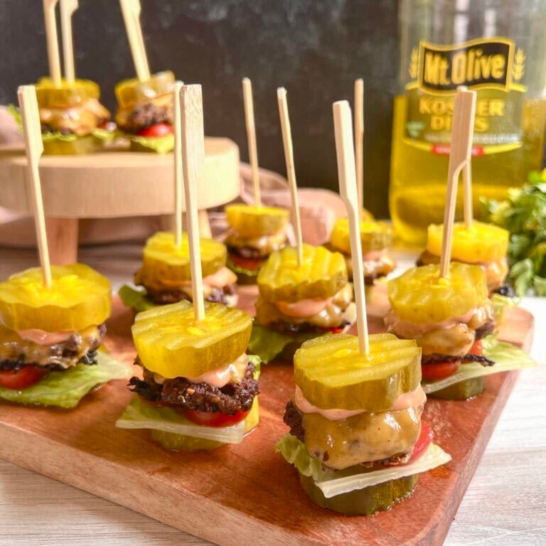 Mini burger sliders with pickle chip as buns on cutting board