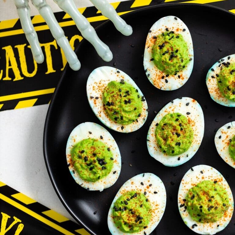 deviled eggs with green food coloring and skeleton hand